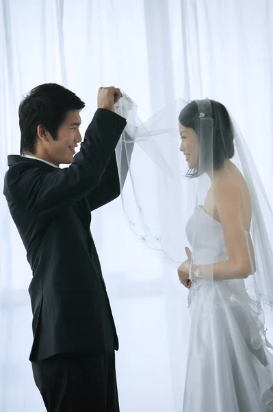 O noivo levanta o véu das noivas — Fotografia de Stock