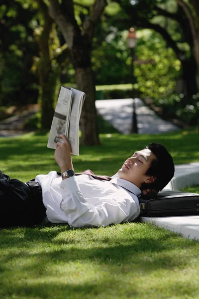 Um homem deita-se e lê o jornal. — Fotografia de Stock