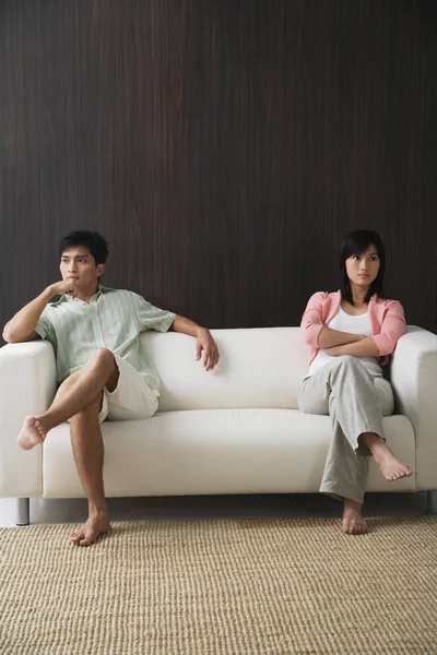Casal sentado em extremidades opostas do sofá — Fotografia de Stock