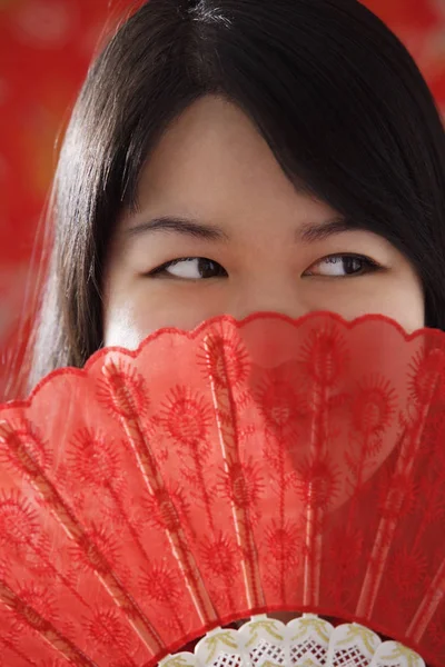 woman looking over hand-held fan