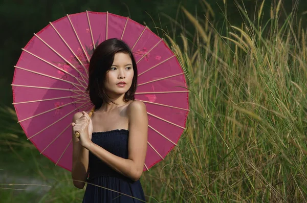 Vrouw in lange gras met parasol — Stockfoto