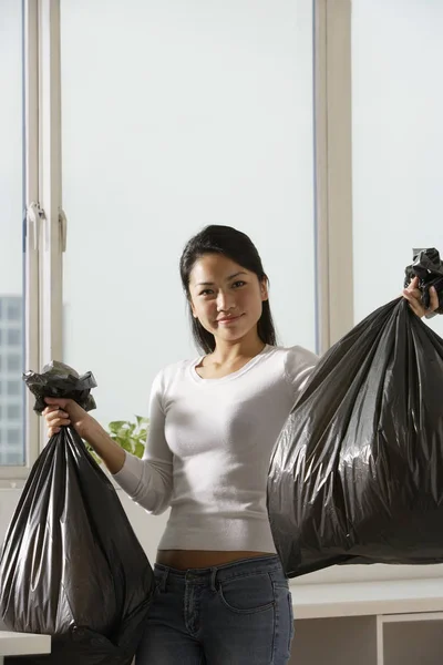 woman holding up trash bags