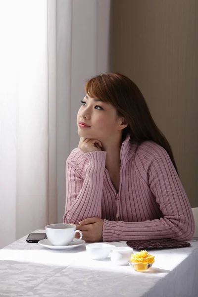 Young woman sitting at table — Stock Photo, Image