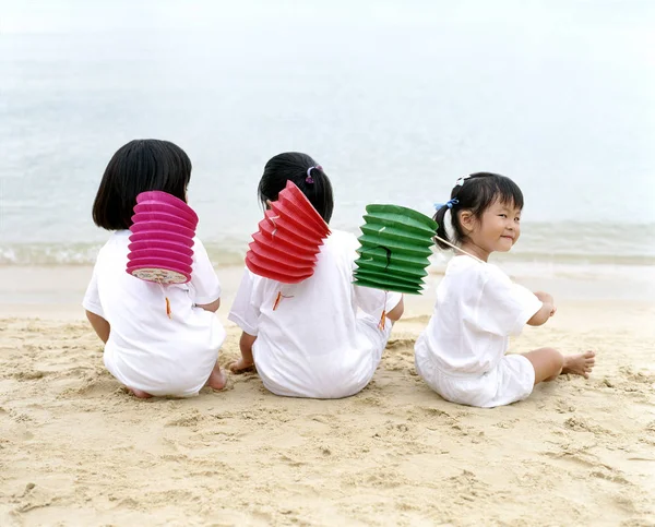 Três crianças sentadas na praia — Fotografia de Stock