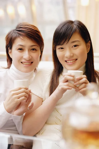 Jovens mulheres segurando xícaras — Fotografia de Stock