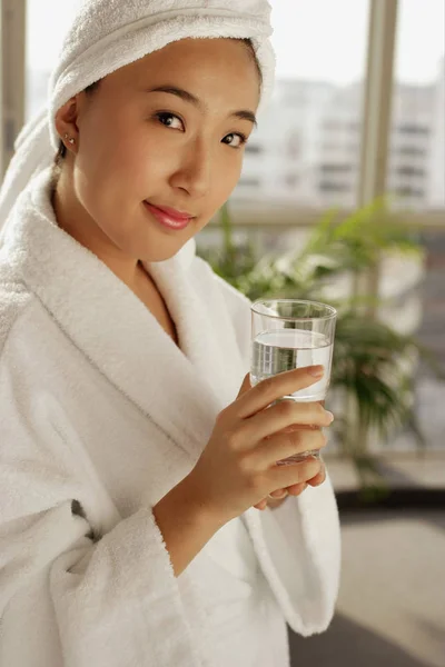 Молодая женщина в халате держит стекло — стоковое фото