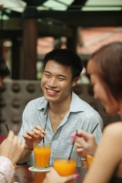 Ung man sitter med vänner, tar en drink — Stockfoto