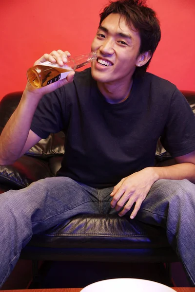 Ung man dricka från ölflaska, tittar på kameran — Stockfoto