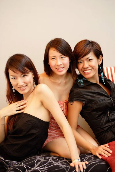 Три молодих жінки, сидячи поруч, дивляться на камеру — стокове фото