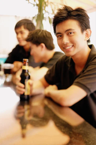 Jeune homme au comptoir du bar tenant de la bière — Photo