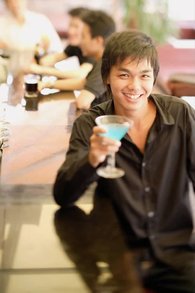 Jeune homme au comptoir bar tenant un cocktail — Photo
