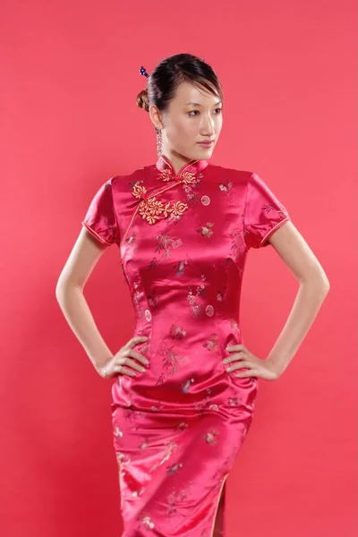 Frau im Cheongsam auf rotem Hintergrund — Stockfoto