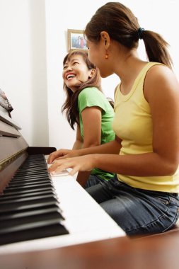 girl playing on piano with mother clipart