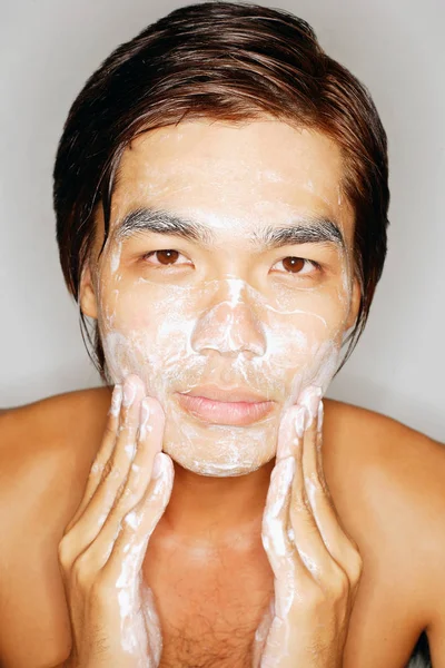 Junger Mann wäscht Gesicht und blickt in Kamera — Stockfoto