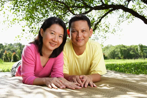 Par som ligger på picknick matta — Stockfoto