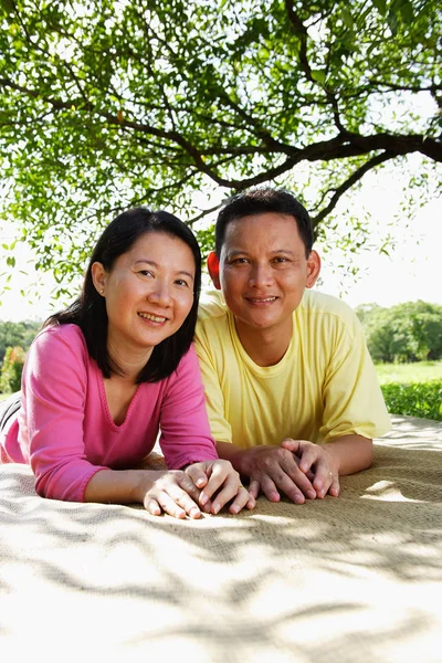 Par som ligger på picknick matta — Stockfoto