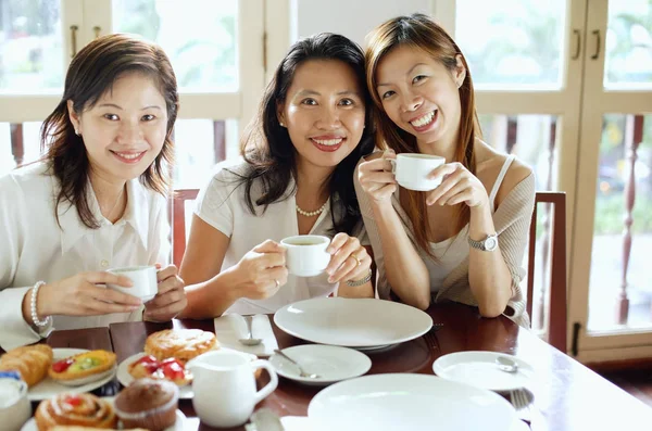 Drie vrouwen in café, glimlachend op camera — Stockfoto