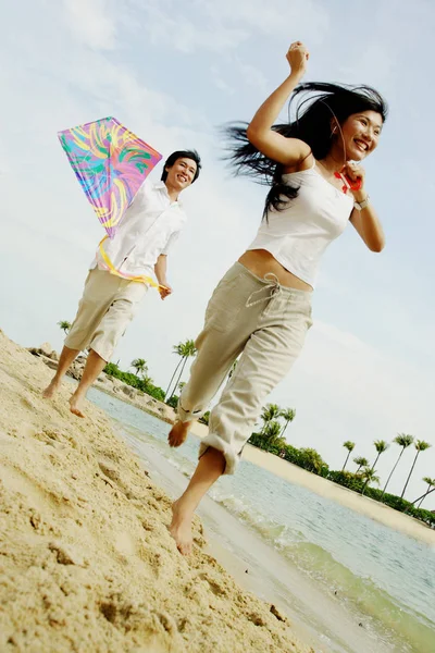 Paar lässt Drachen am Strand steigen — Stockfoto