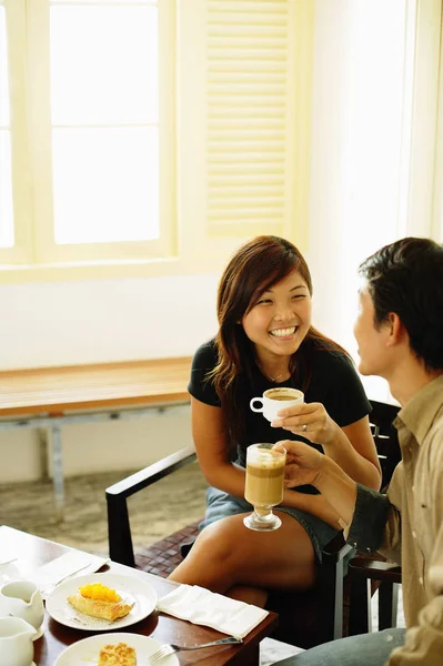 Couple at cafe, holding coffee mugs — Stock Photo, Image