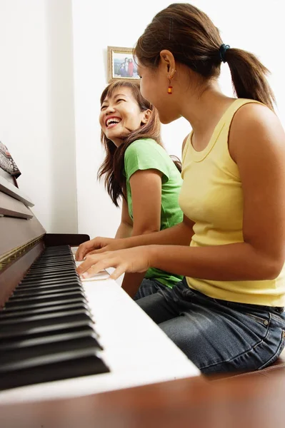 Дівчина грає на піаніно з матір'ю — стокове фото
