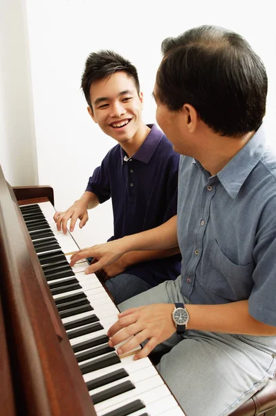 Pojke spela på piano med far — Stockfoto