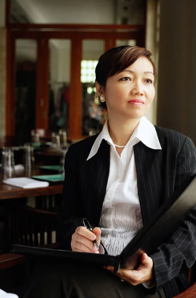 Businesswoman in restaurant holding pen and folder