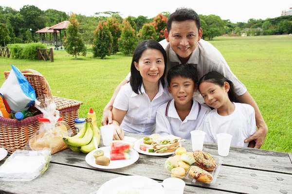 Familjen sitter vid picknickbord — Stockfoto