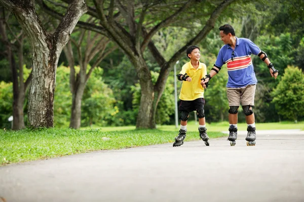 Padre e hijo patinando en línea en el parque — Foto de Stock