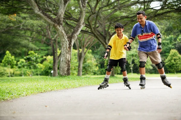 Far och son, i-line skating i park — Stockfoto