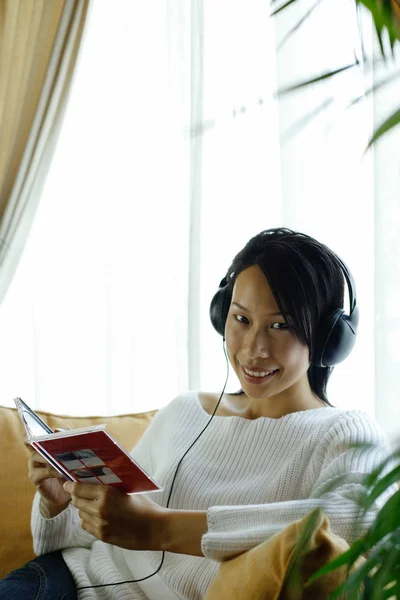 Femme sur canapé portant un casque — Photo