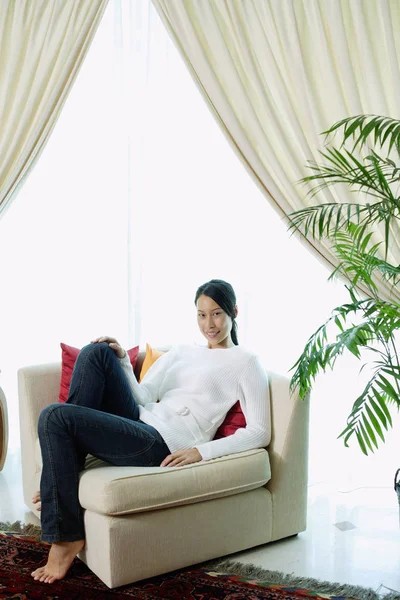 Mulher sentada no sofá em casa — Fotografia de Stock