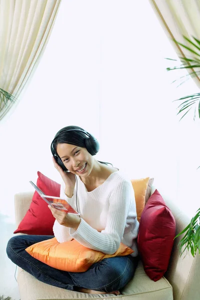 헤드폰을 착용 하는 소파에 앉아 여자 — 스톡 사진