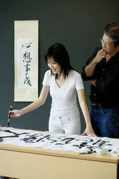 Man and woman writing Chinese calligraphy