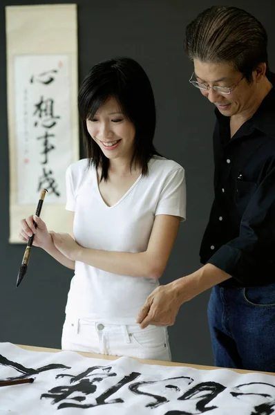 Man and woman writing Chinese calligraphy