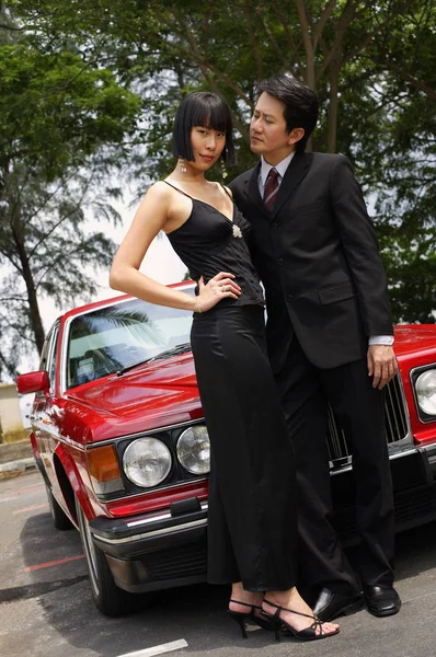 Пара, стоящая перед красной машиной — стоковое фото