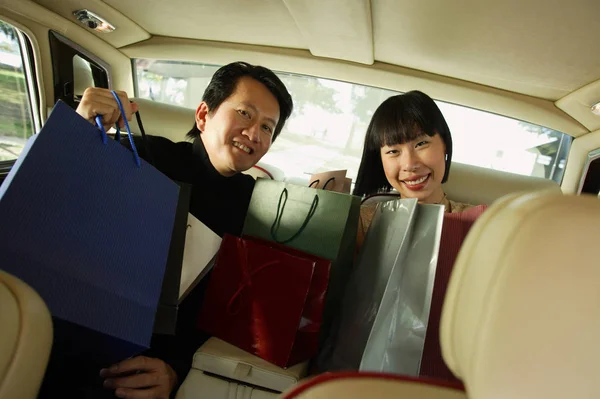 Paar zitten in auto met shopping tassen — Stockfoto