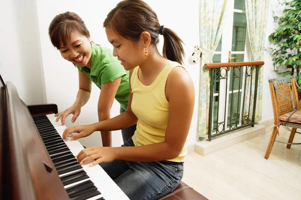 Flicka som leker på pianot med mamma — Stockfoto