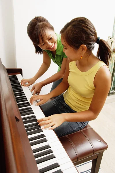 Flicka som leker på pianot med mamma — Stockfoto