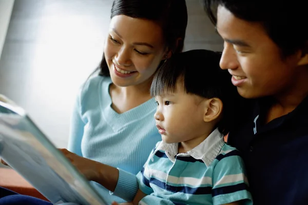 Familia con un niño leyendo un libro — Foto de Stock