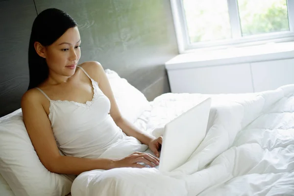 Vrouw in bed met behulp van laptop — Stockfoto