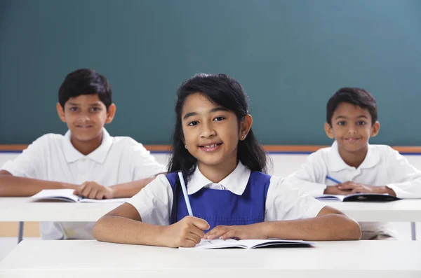 Three students smile at camera, girl in center — Stock Photo, Image