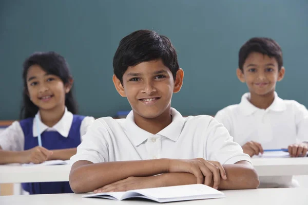 Drie studenten glimlachend in de camera, jongen in centrum — Stockfoto