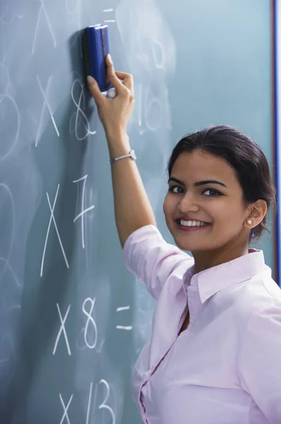 Profesora sonriendo como ella borra en pizarra —  Fotos de Stock