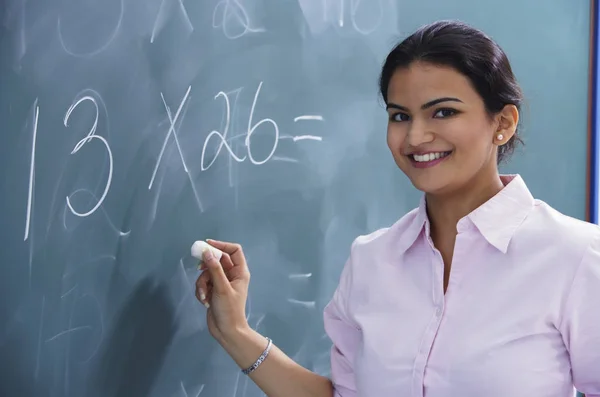 Profesora sonriendo mientras escribe en pizarra —  Fotos de Stock