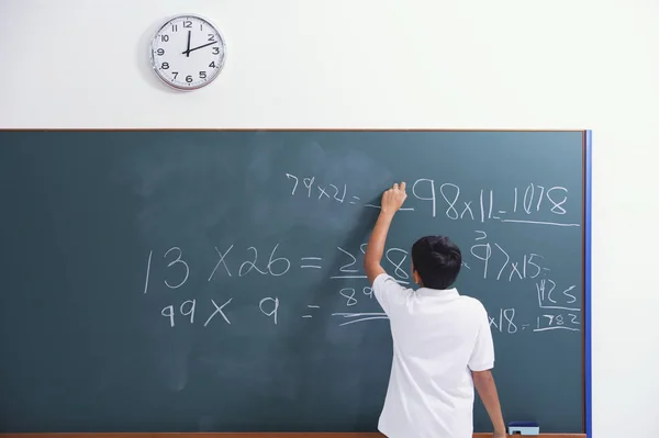 Boy standing at chalkboard — Stock Photo, Image