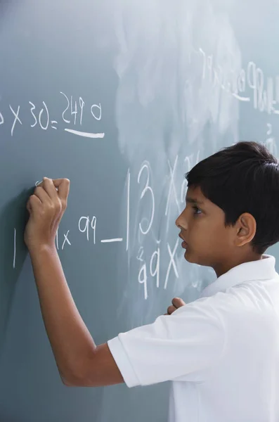 Boy standing at chalkboard — Stock Photo, Image