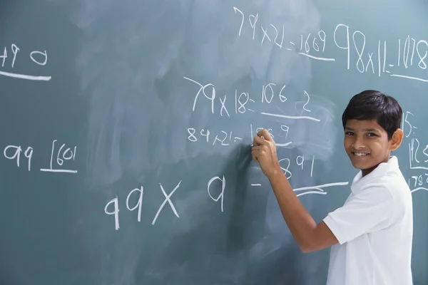 Boy at chalkboard, smiling at camera — Stock Photo, Image