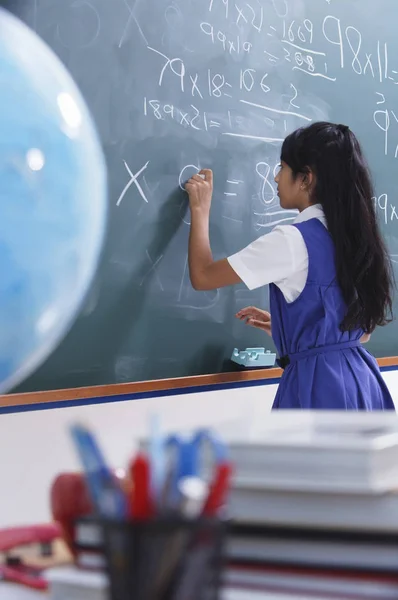 Schoolgirl in front of chalkboard — Stock Photo, Image