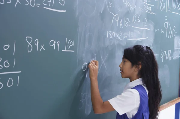 Schoolgirl in front of chalkboard — Stock Photo, Image