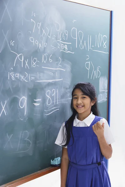 Schoolgirl in front of chalkboard — Stock Photo, Image